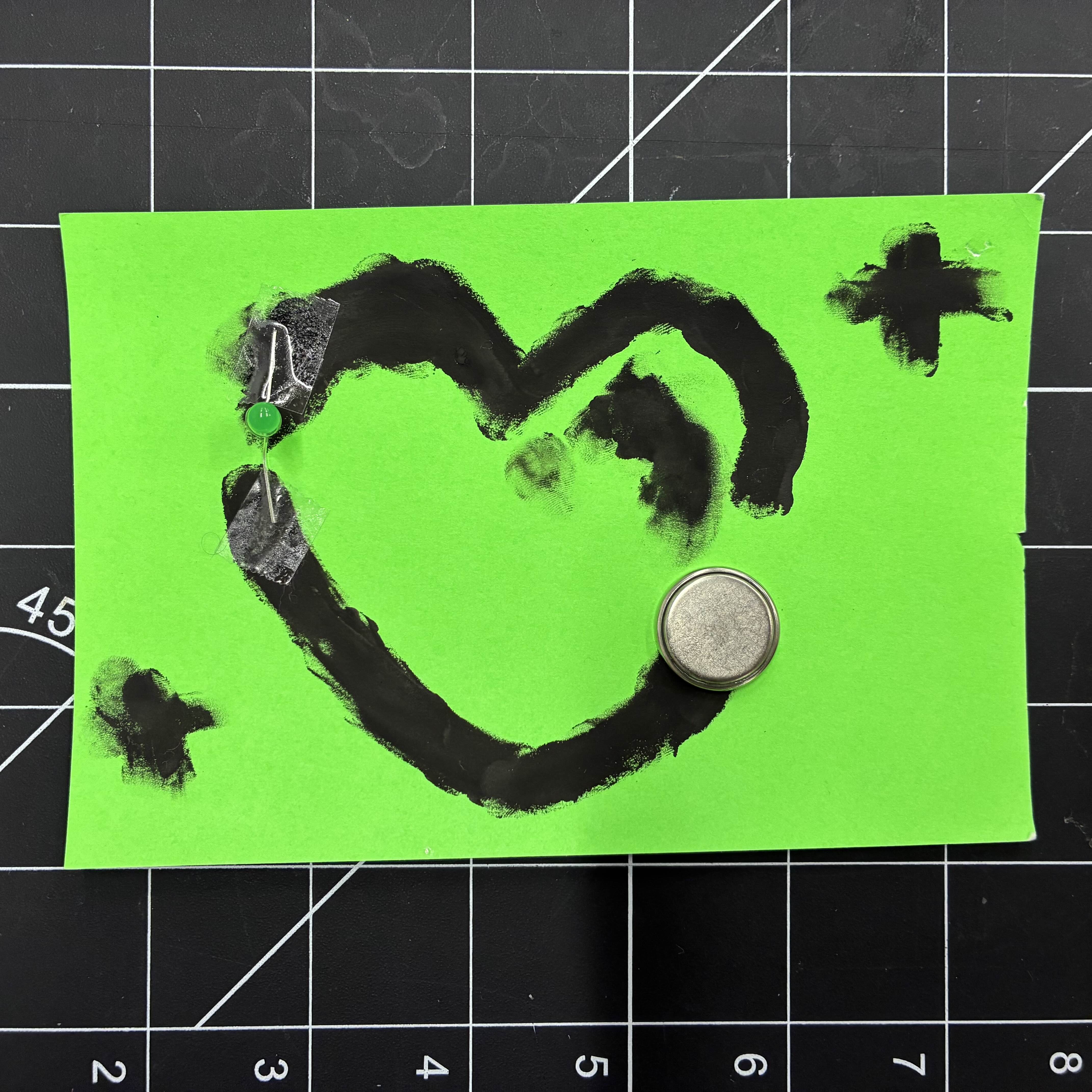 This is the heart made of conductive paint. I taped an LED light to fill the gap in the heart and then placed a battery on the other end.