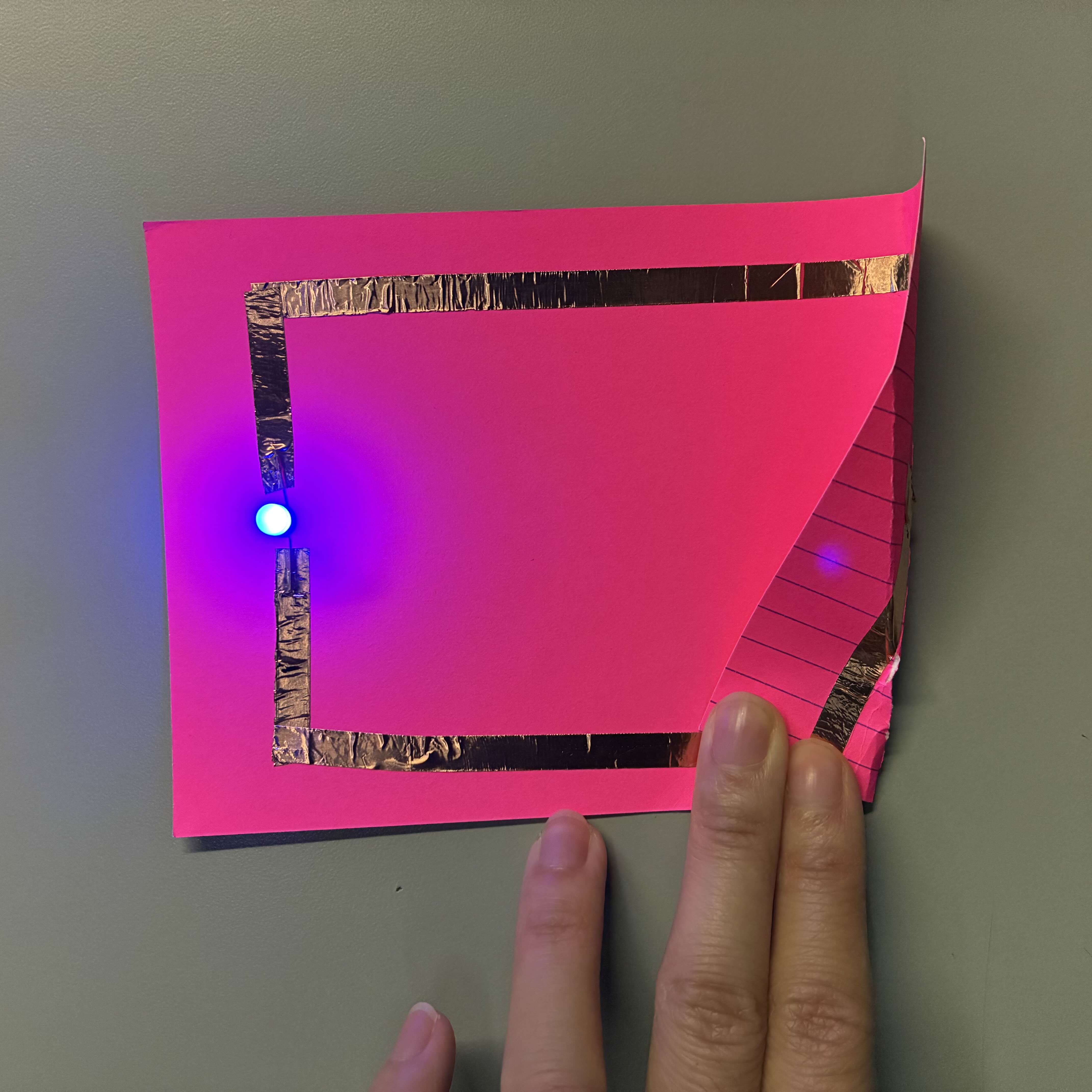 This was my simple circuit with the battery connecting the copper tape to make the light turn on. I put the tape over the LED light instead of putting the LED light over the copper tape and it worked like a charm while also being extra secure.