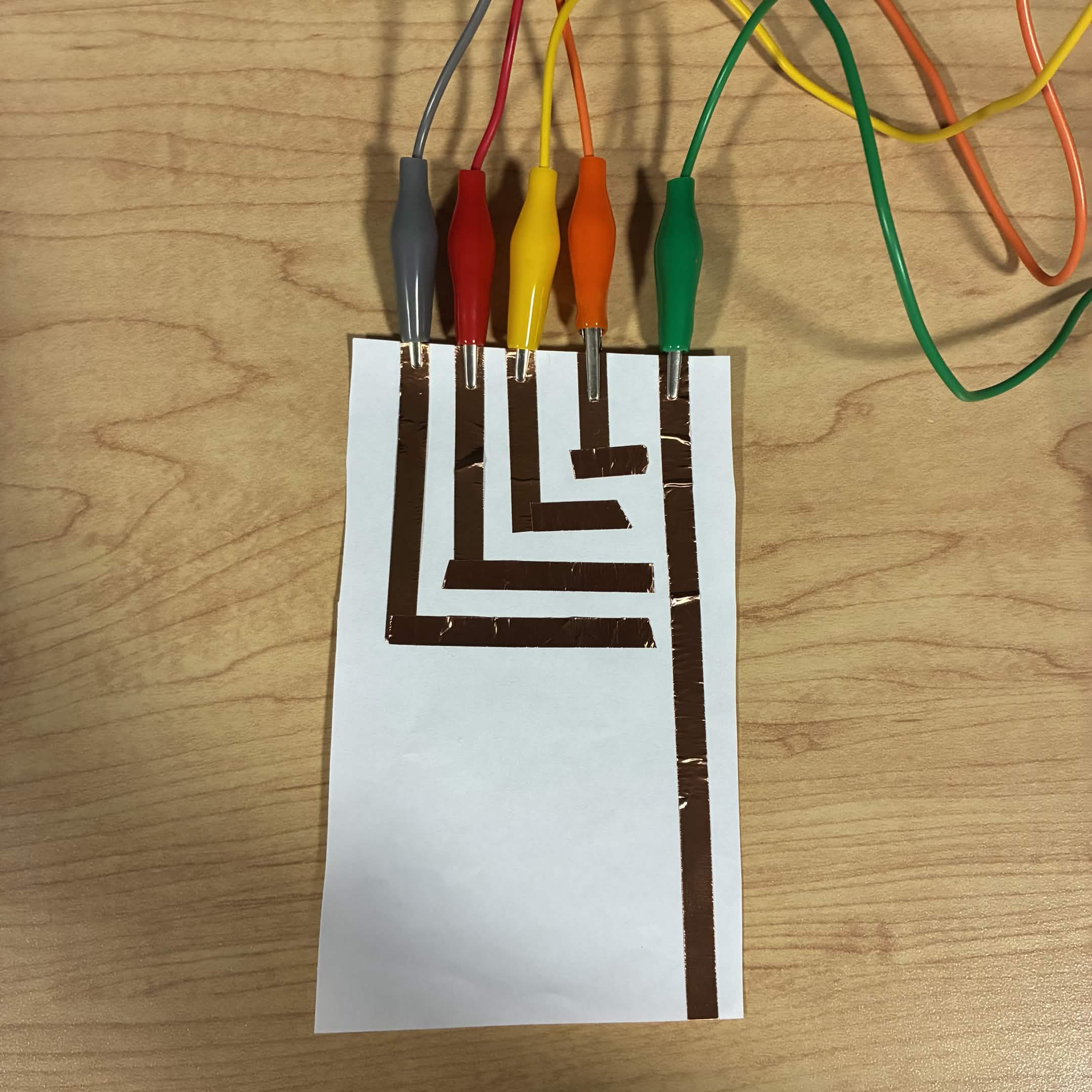 I added enough circuits to connect to all the arrows on the Makey Makey. The yellow wire is connected to the down button, the orange wire is connected to the left button, the red wire is connected to the up button, the grey wire is connected to the right button and green is connected to ground.